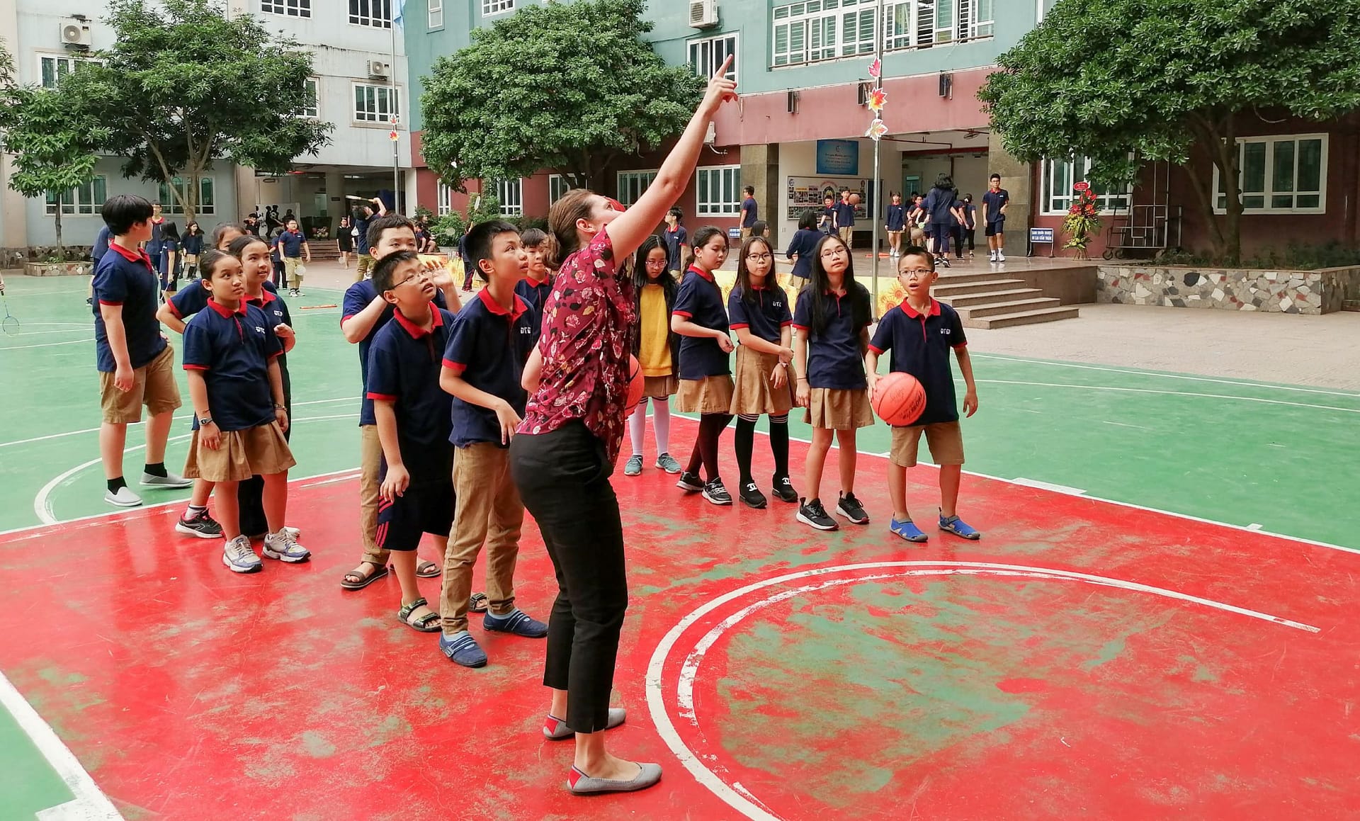 A teacher shows a class how to play basketball